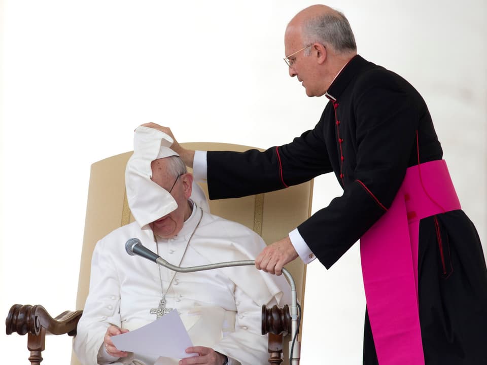 Papst bekommt durch Windstoss Teil des Gewandes ins Gesicht.