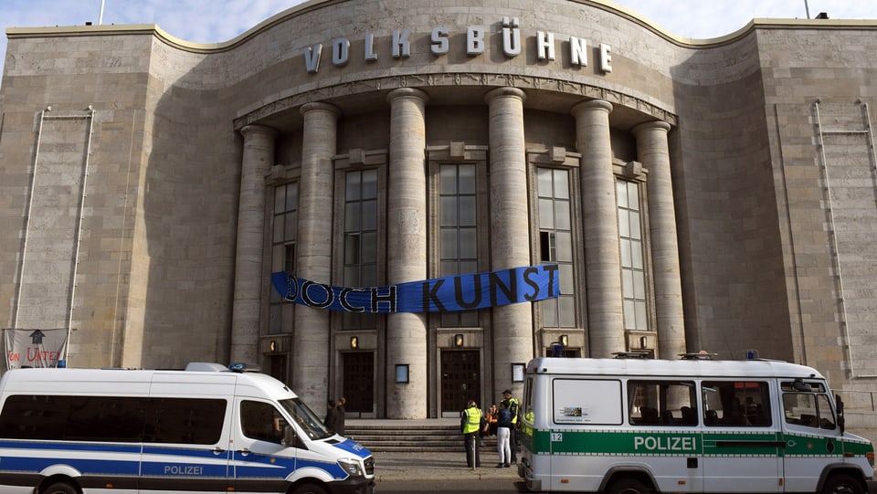 Vor der Berliner Volksbühne stehen Polizei-Autos.