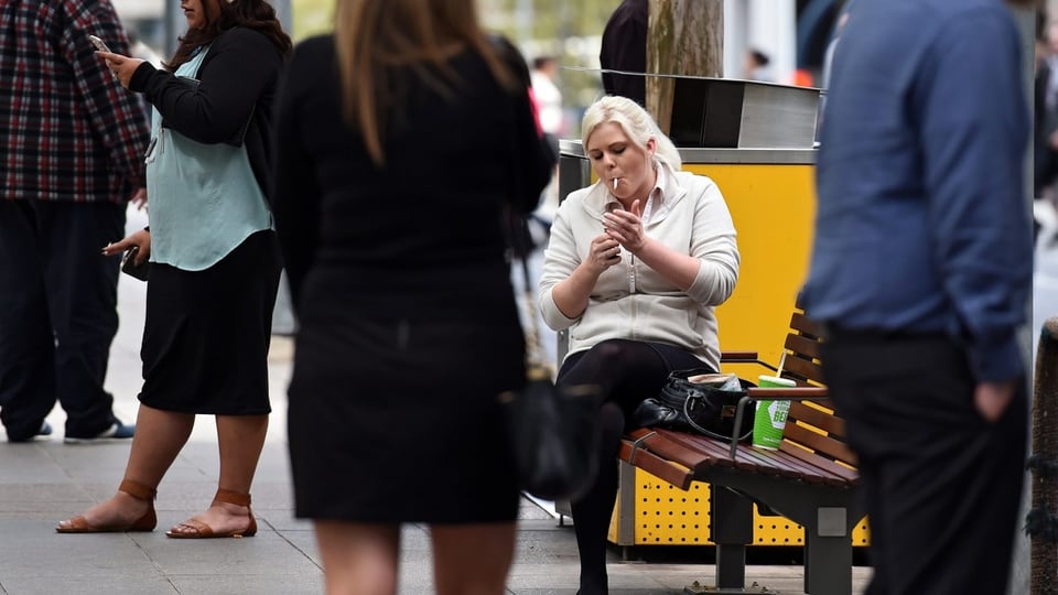 Eine Frau in Australien zündet sich eine Zigarette an.