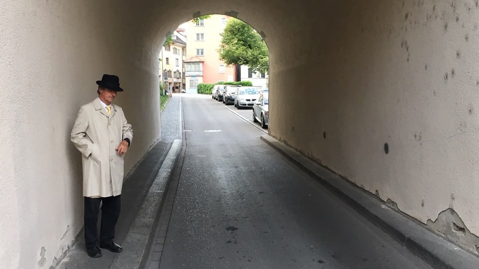 Ein Mann mit Hut steht in einem Tunnel.