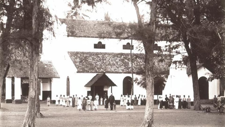 Schwarz-Weiss-Foto: Vor einer grossen Kirche stehen Menschen. 