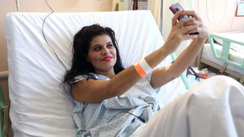 Patientin macht im Krankenhausbett ein Selfie