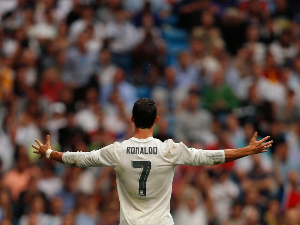 Cristiano Ronaldo lässt sich mit ausgebreiteten Armen von der Real-Fankurve feiern.