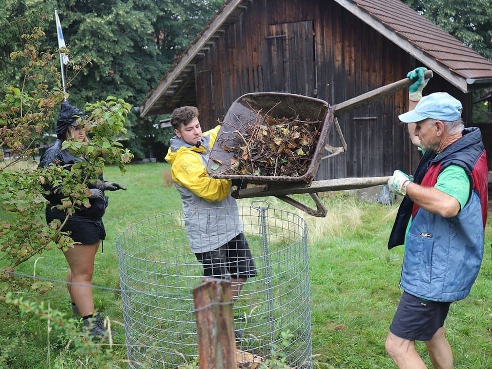 Der «neue» Kompost der Gartenbauer von Oberwil Zwei Männer befüllen einen Kompost mit Ästen und Blättern.