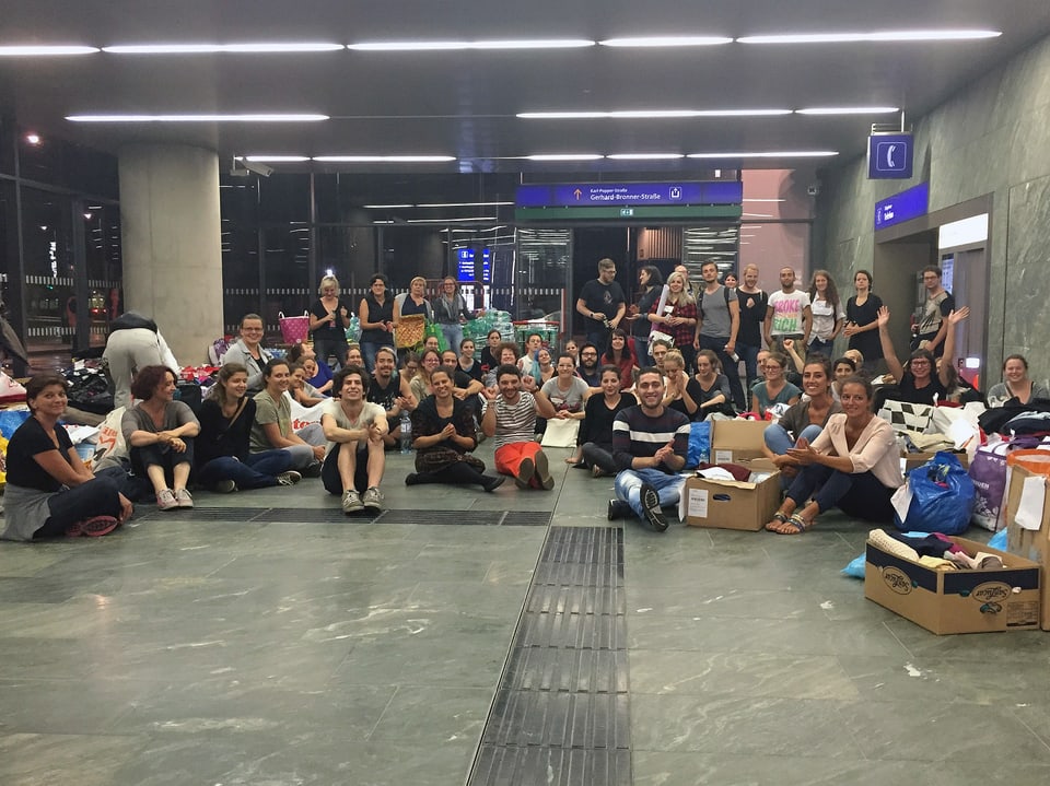 Helfer und Helferinnen sitzen im Wiener Hauptbahnhof am Boden
