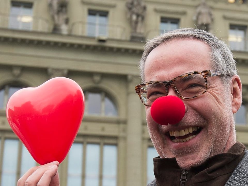 Der Stadtpräsident mit einer Clownnase und einem roten Herz in der Hand.