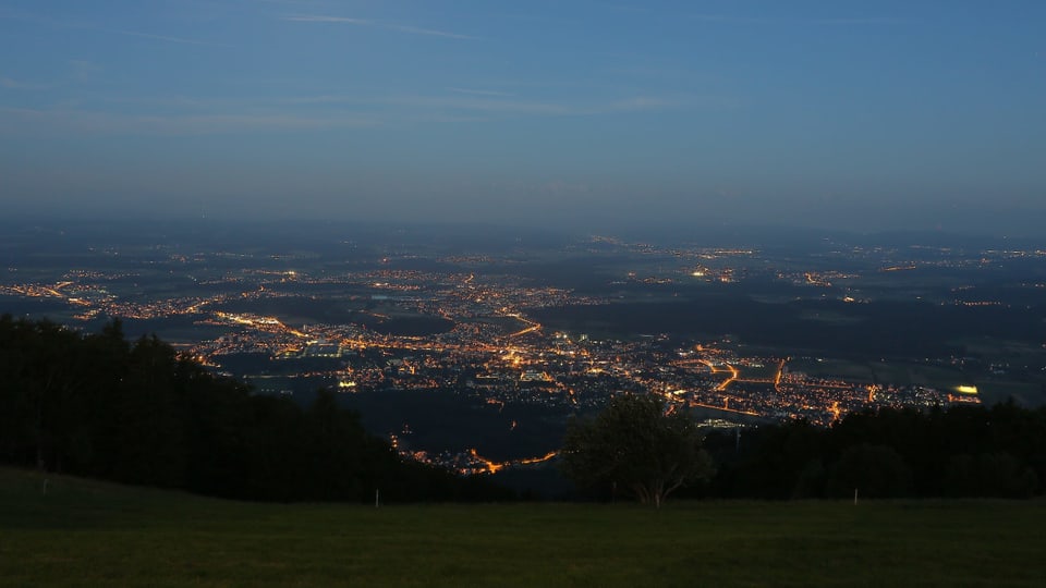 Aussicht vom Berg bei Nacht: Leuchtende Punkte von Häusern und Strassenlampen