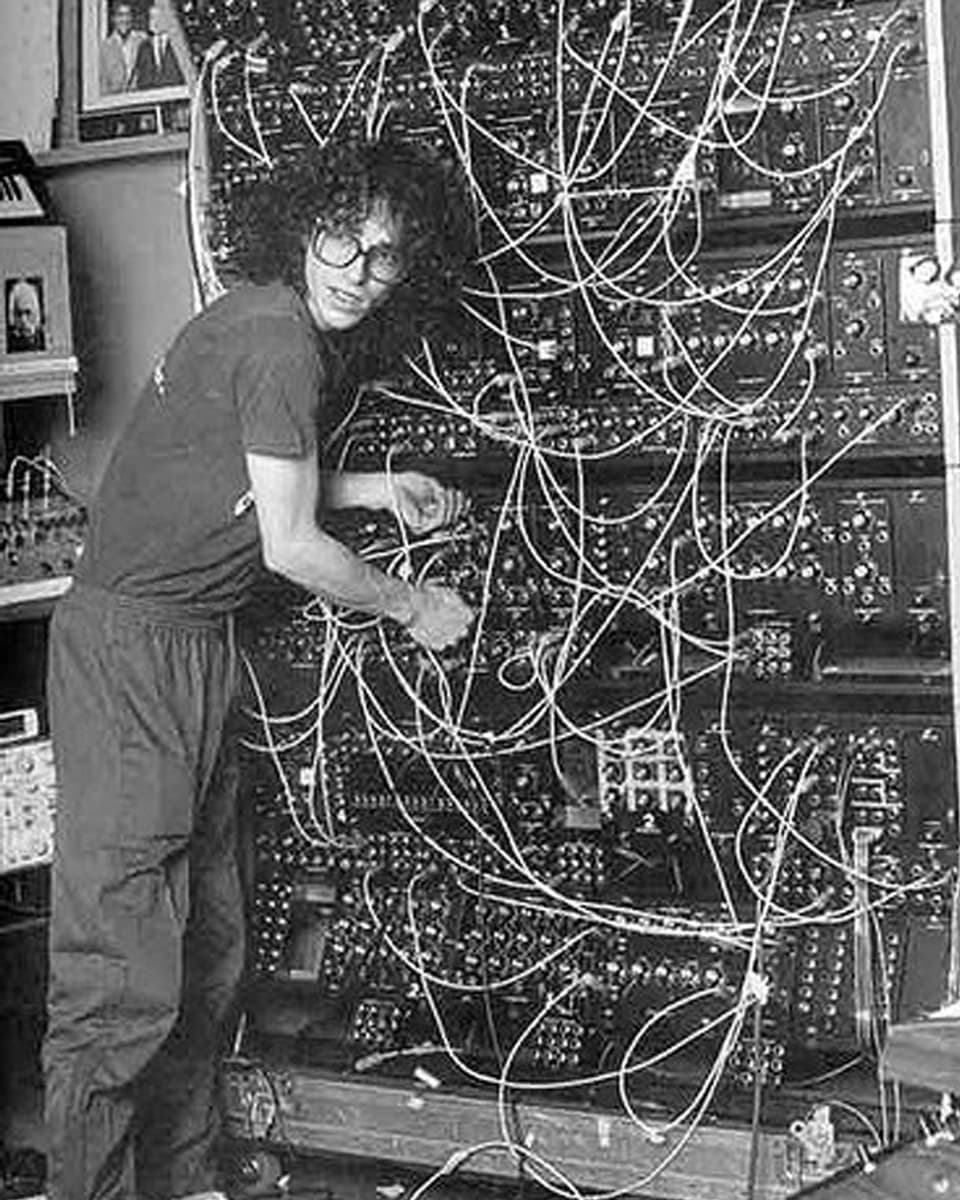 Steve Porcaro von Toto steht vor einem riesigen modularen Synthesizer mit vielen Kabeln und Knöpfen. 