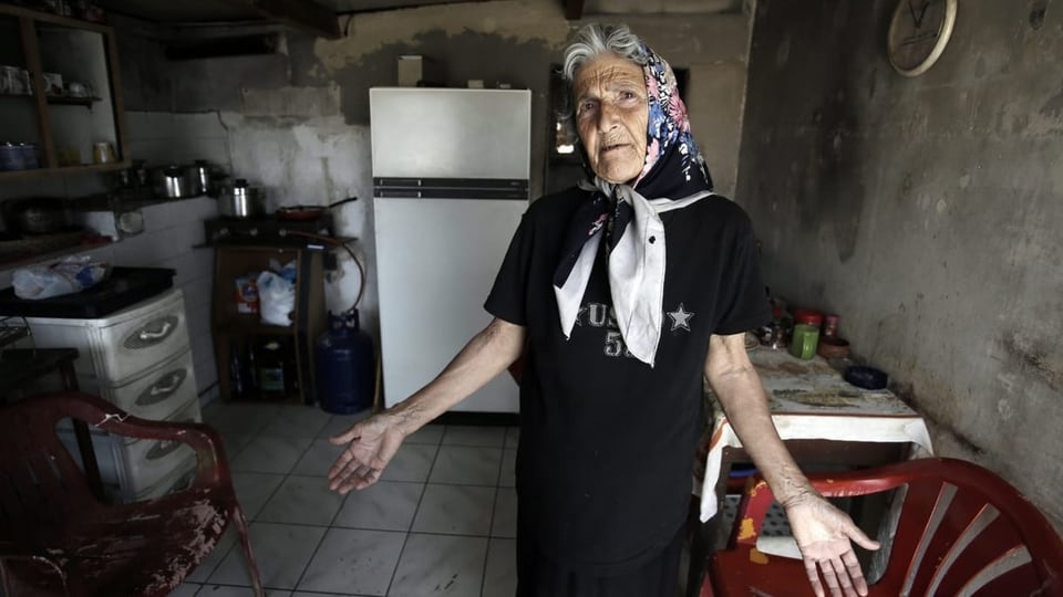 Eine griechische Seniorin steht in ihrer kleinen Küche.