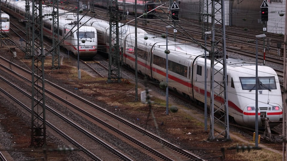 Drei Züge der Deutschen Bahn stehen auf Gleisen.