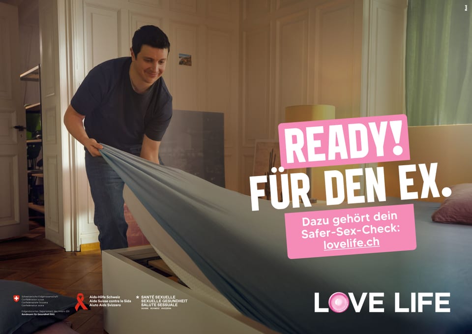 Mann bereitet Schlafzimmer vor, zieht Bettlaken glatt, Werbebotschaft für Safer-Sex.