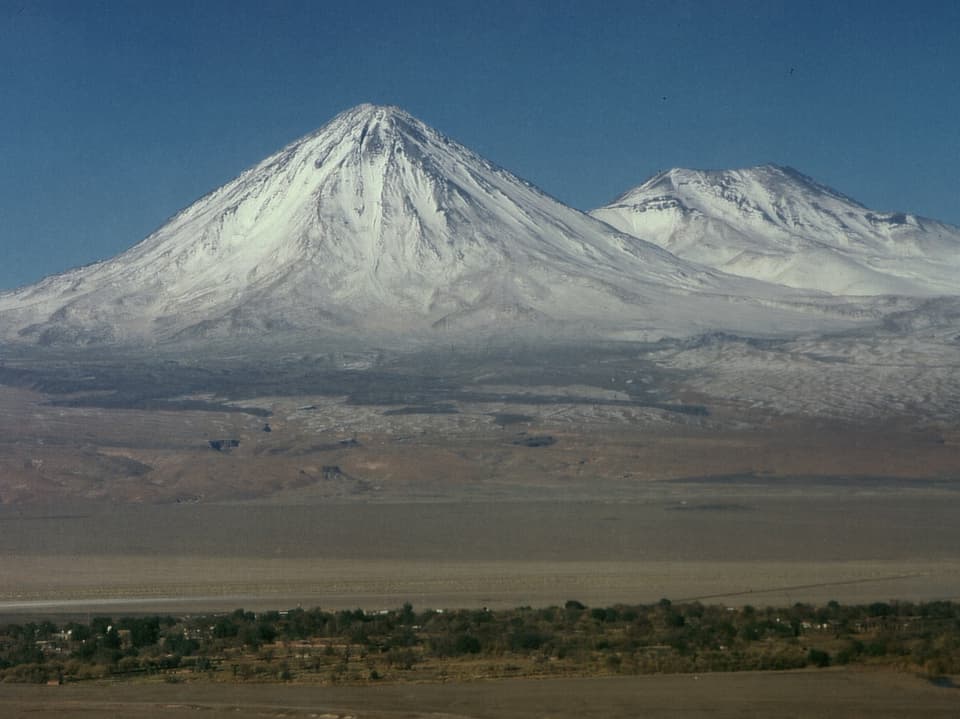 Vulkan am Fuss der Atacamawüste. Er ist teilweise schneebedeckt.