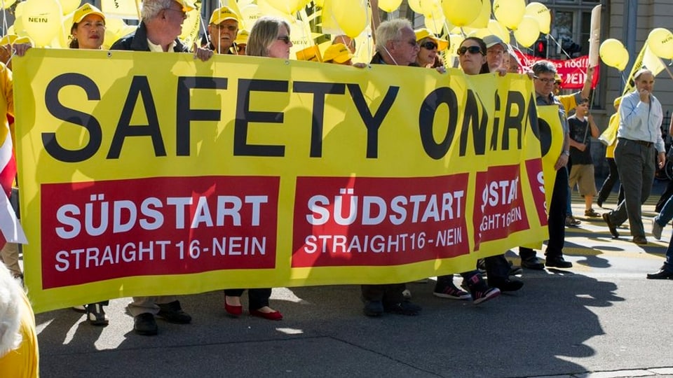 Demonstranten mit einem gelben Banner mit dem Schriftzug «Südtart Straight 15 – Nein»