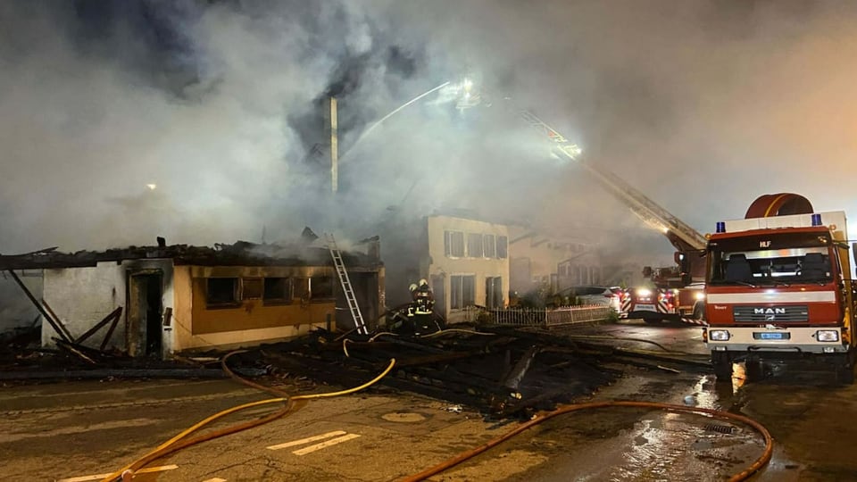 Feuerwehr im Einsatz, Rauch steigt aus einer Brandruine auf