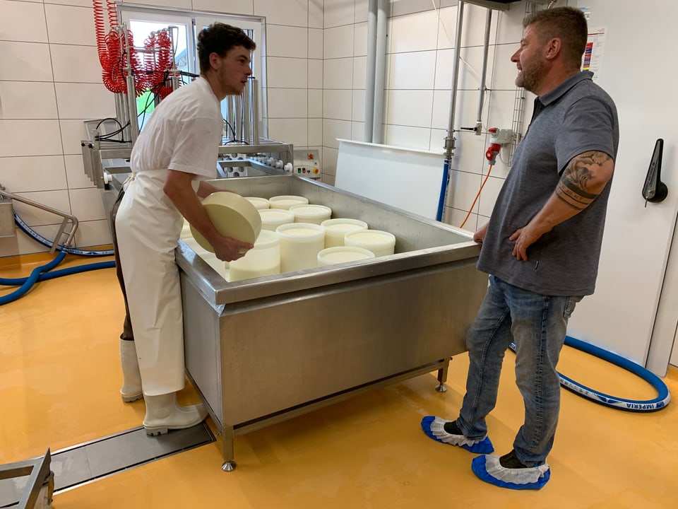 Zwei Männer bei der Käseherstellung in einem Gespräch.