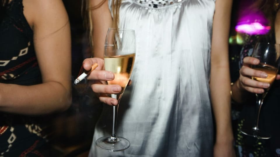 Junge Frau mit einer Zigarette und einem Glas Champagner.