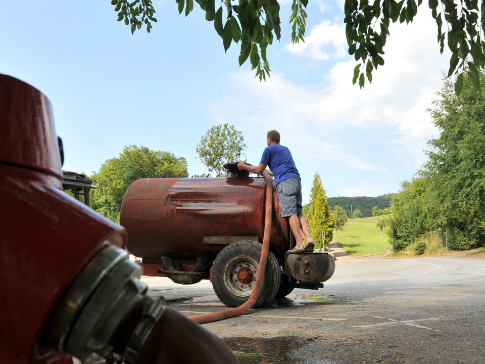 Ein Bauer pumpt Wasser von einem Hydranten in seinen Tank-Anhänger.