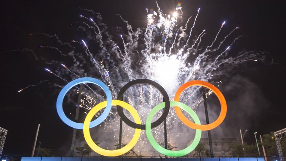 Olympische Ringe mit Feuerwerk im Hintergrund