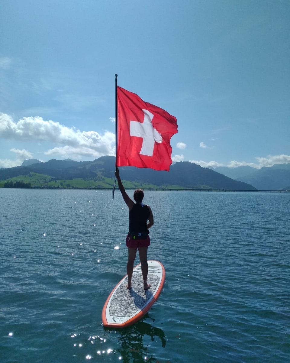 Surferin auf See mit Schweizer Fahne.