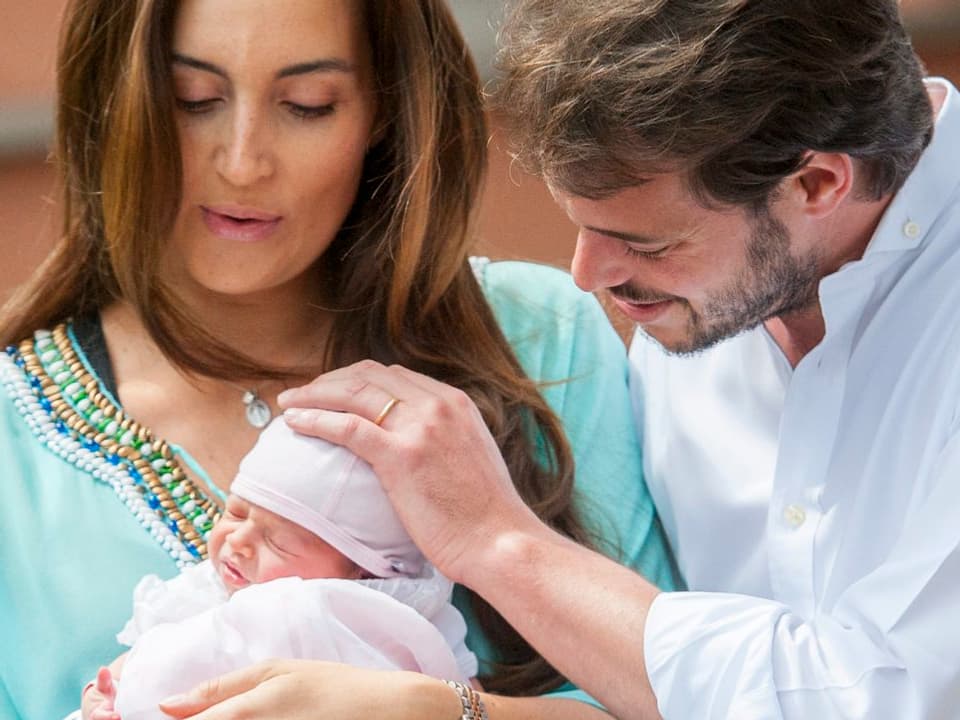 Marie, blaues Dress, Félix, Weisses Hemd, mit Neugeborenen in weissem Babykleid, streicheln über den Kopf