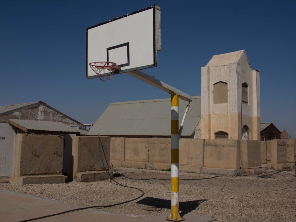 Ein Basketballkorb und im Hintergrund eine einfache Kirche.