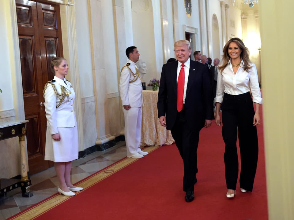 Melania Trump und ihr Mann schlendern durch einen Gang im Weissen Hauses.