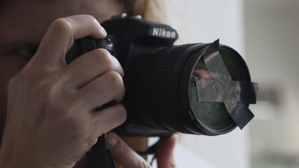 Eine Kameralinse ist mit zwei Klebestreifen verdeckt.