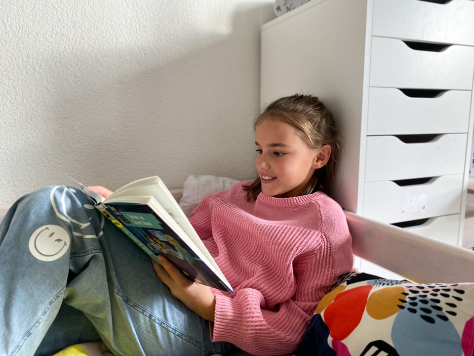 Aline liegt auf dem Bett und liest ein Buch