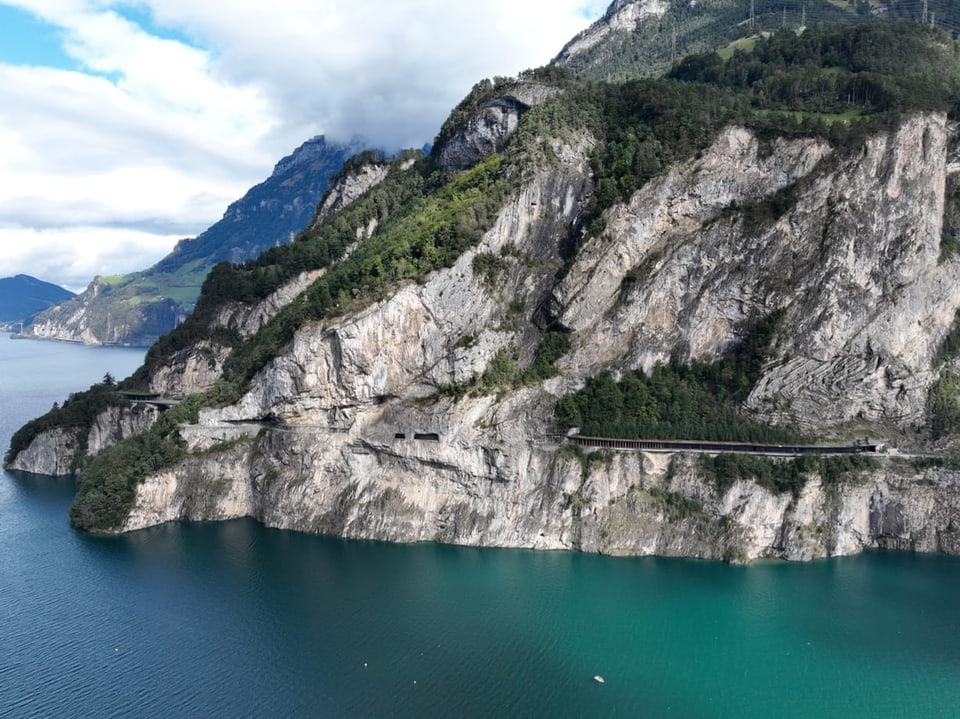 Paisagem montanhosa com lago e estrada ao longo das rochas.