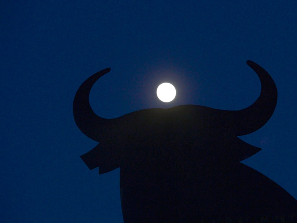 Mond am Nachthimmel zwischen den Hörnern einer Stierskulptur