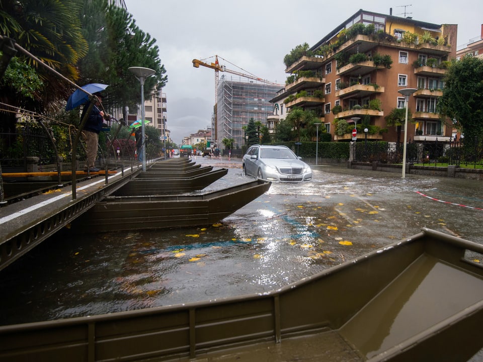 Neben einem Steg auf Weidlingen fährt ein Auto durch eine überschwemmte Strasse