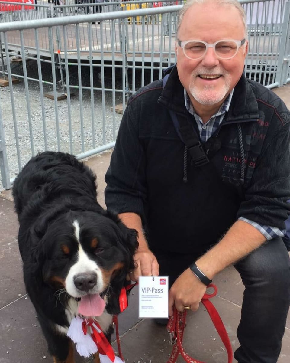 Mann mit Berner Sennenhund. Der Hund trägt eine Vip-Karte um den Hals.