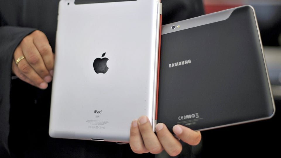 Ein Mann zeigt einen Apple- und Samsung Tablet-Computer. (keystone)