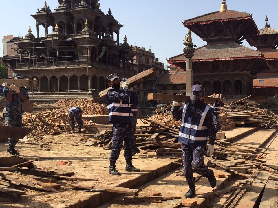 Sicherheitskräfte tragen Holzstücke vom Durbar Platz in Kathmandu.