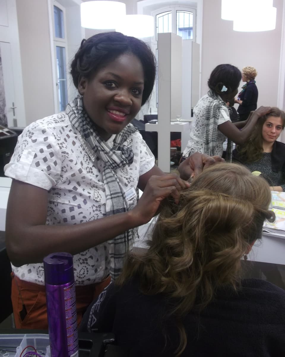 Die afrikanische Coiffeuse Loide Kondja frisiert einer Kundin die Haare.
