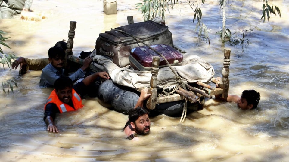 Vertriebene retten ihre Habseligkeiten durch ein überflutetes Gebiet am Stadtrand von Peshawar (28. August 2022).