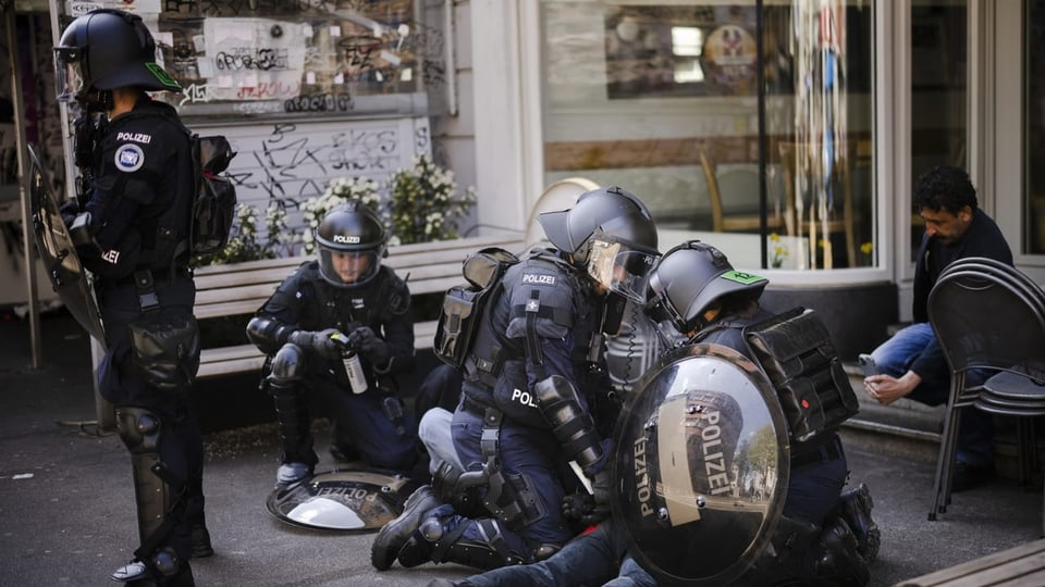 Vermummte Polizisten drücken Mann an Boden.