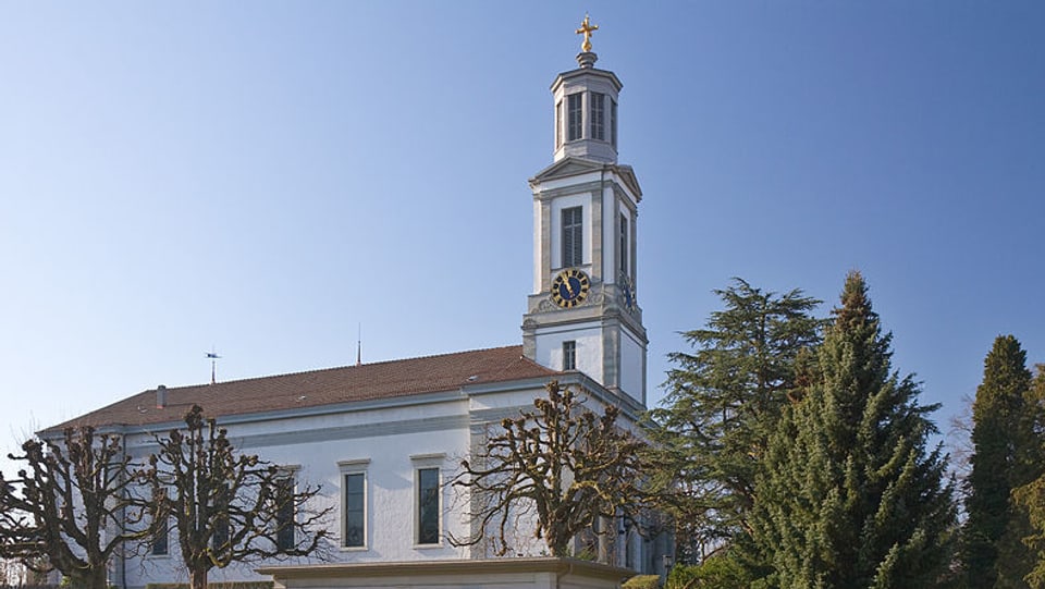 Die Kirche Neumünster mit dem spitzen Turm und dem goldenen Kreuz obendrauf. 