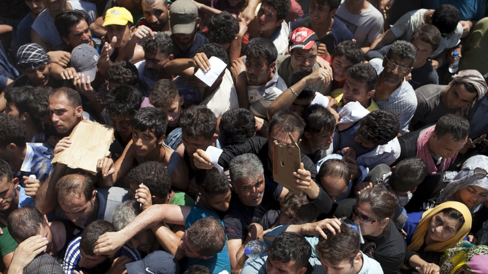 Dutzende Migranten stehen dicht gedrängt in der Hitze
