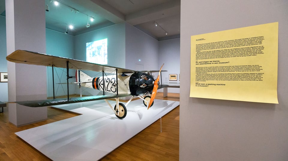 Man sieht einen Flieger im Museum. Nebenan ein Post-It mit der Aufschrift «Was kommt als nächstes ins Museum, etwa eine Waschmaschine?»
