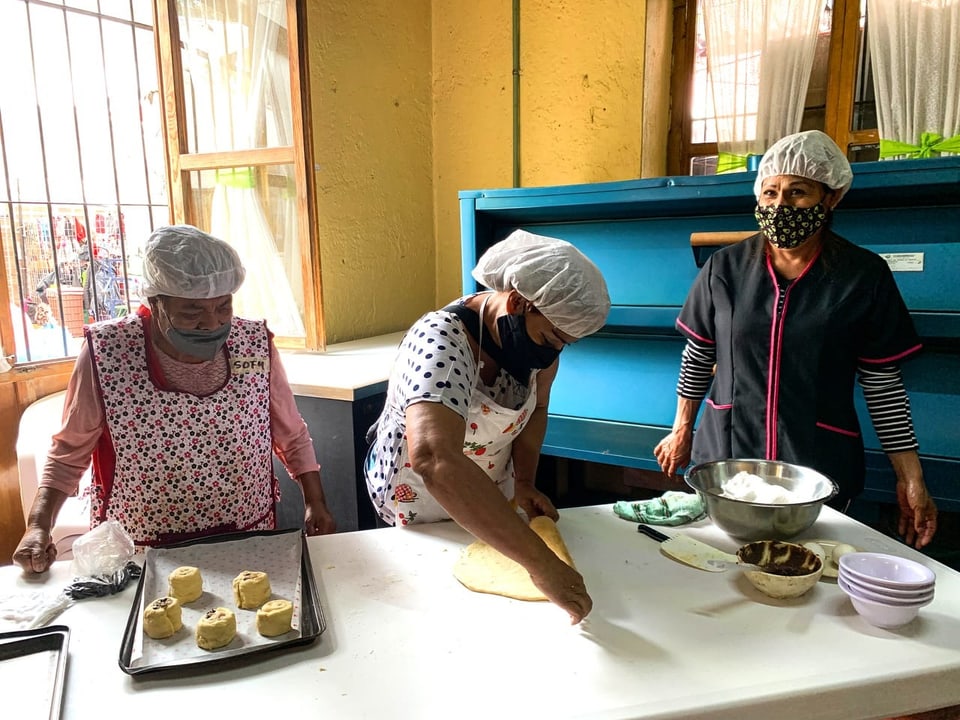 Three women baking bread at Casa Xochiquetzal.