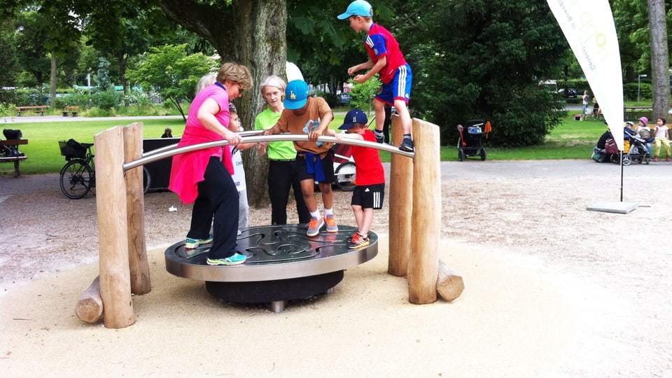 Eine Gruppe aus Kindern und Erwachsenen auf einem der Geräte im Schützenmattpark.