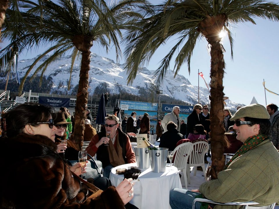 Menschen unter Palmen auf zugefrorenem See in St. Moritz