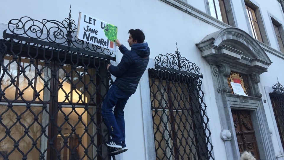 Mann hängt Plakat auf: Let us save nature
