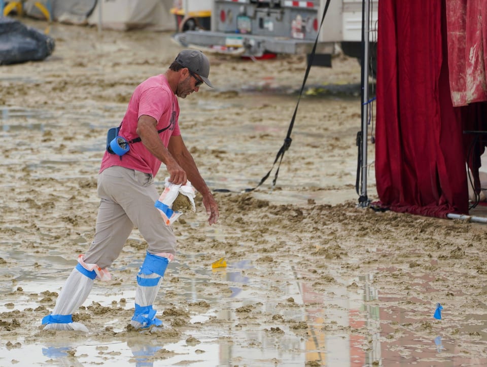 Mann watet mit angeklebten Plastiksäcken an den Füssen durch Match