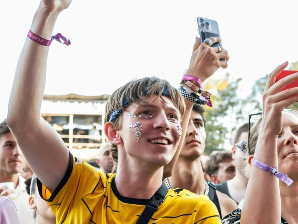 Ein junger Mann mit Glitzer im Gesicht am Gurtenfestival 2023