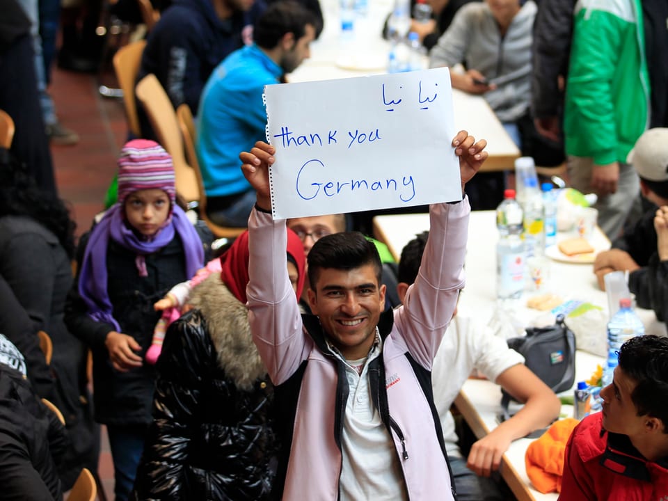 Ein Flüchtling hält in einem Registrierungszentrum in Deutschland ein Schild hoch mit den Worten Thank you, Germany