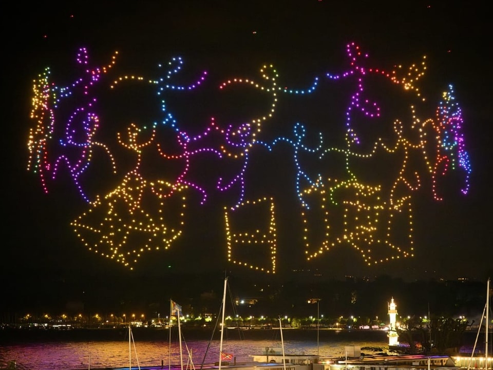 Ein buntes Muster aus kleinen Punkten leuchtet über einem See.