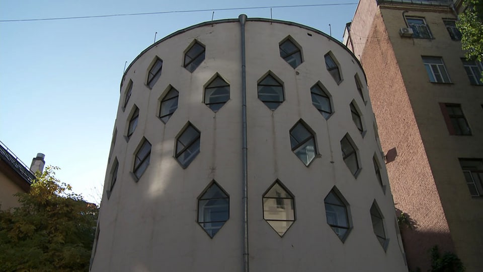 Blick auf ein Gebäude in Form eines Zylinders mit sechseckigen Fenstern.