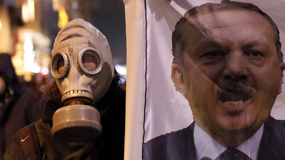 Demonstrant mit Gasmaske hält ein Plakat mit dem Konterfei Erdogans hoch.